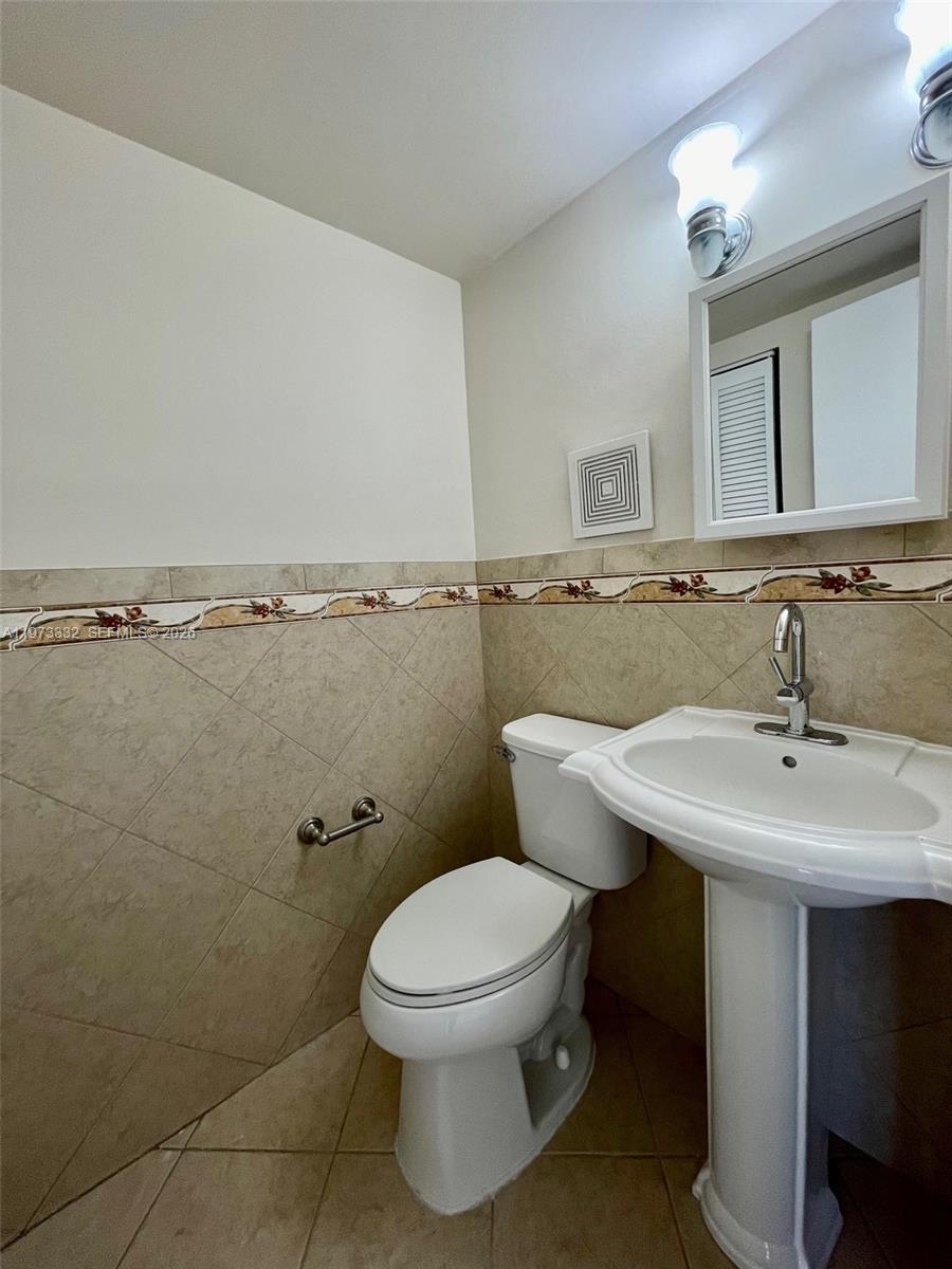 1035 West 77th Street, Unit 412 Hialeah, FL 33014 - Photo 10 of 20 a bathroom with a toilet a sink and mirror