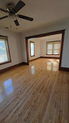 a view of an empty room with wooden floor and a window