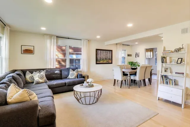 a living room with furniture and a dining table with bookshelf