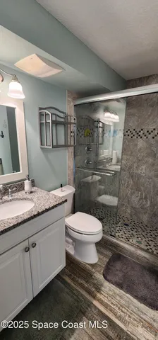 a bathroom with a granite countertop sink a toilet and a mirror