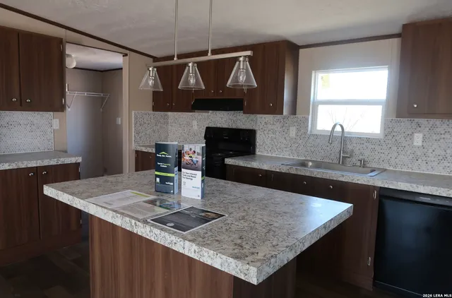 a kitchen with a kitchen island a sink a counter top space and living room