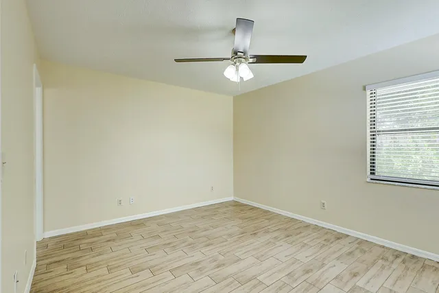 a view of an empty room with wooden floor and a window