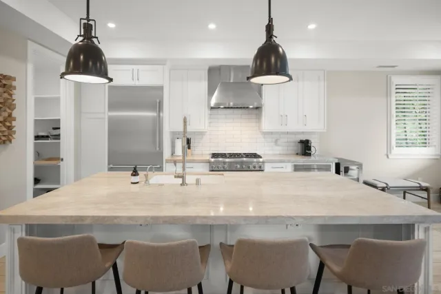 a kitchen with stainless steel appliances granite countertop a sink a stove and chairs