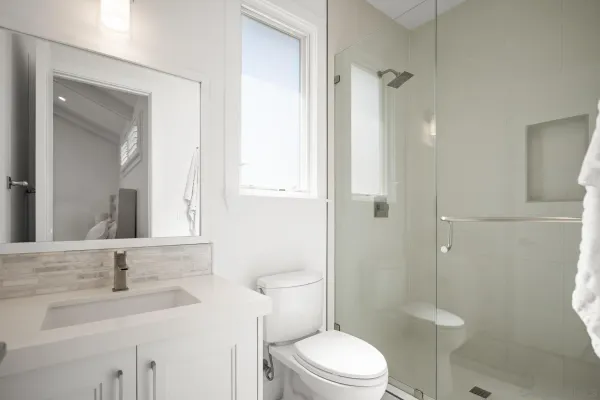 a bathroom with a toilet sink vanity granite and shower