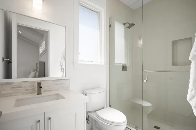 a bathroom with a toilet sink vanity granite and shower