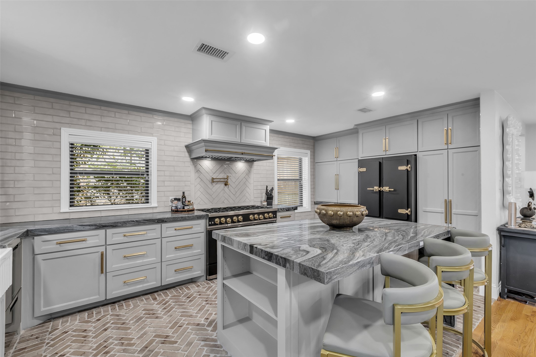 a kitchen with stainless steel appliances granite countertop a stove top oven a refrigerator a sink and chairs