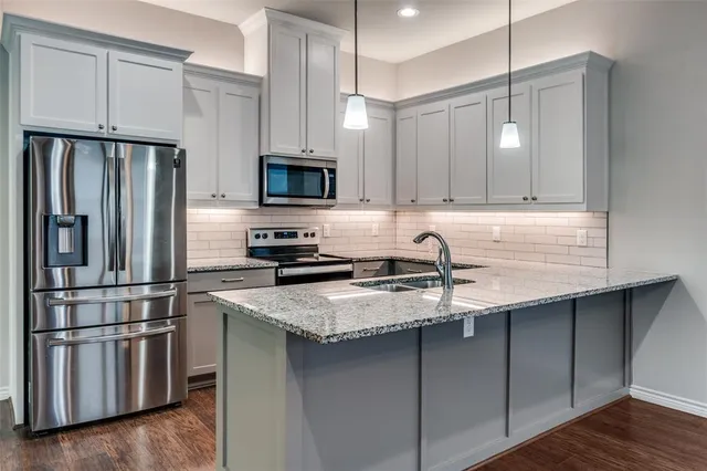 a kitchen with stainless steel appliances granite countertop a refrigerator a stove a sink and a microwave