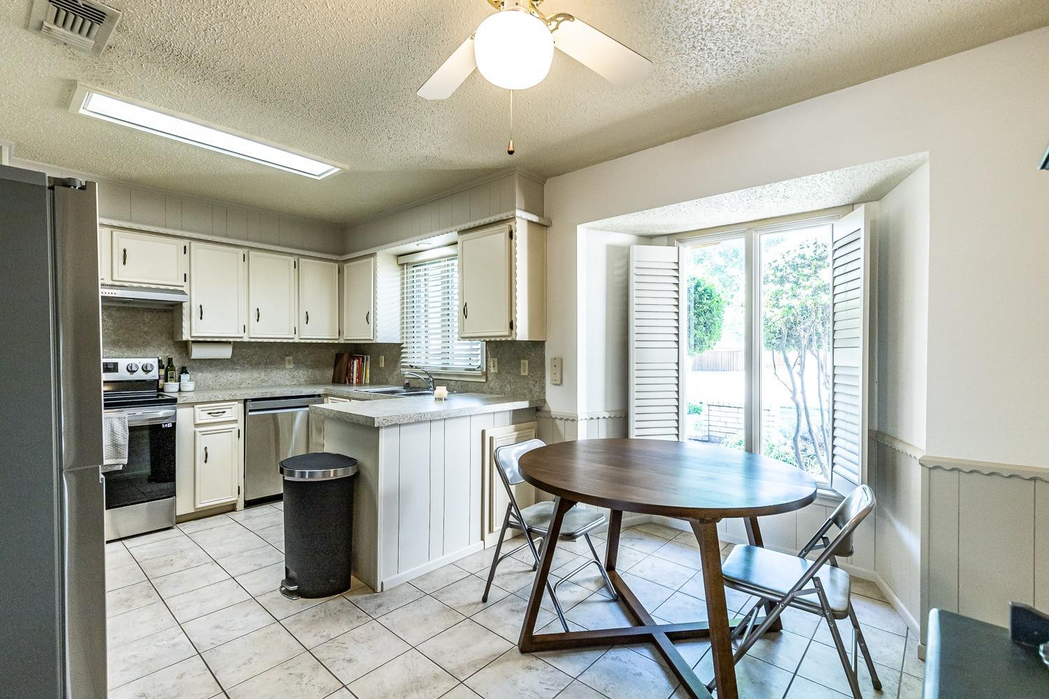 4602 63rd Street Lubbock, TX 79414 - Photo 12 of 37 a kitchen with a dining table chairs stainless steel appliances and cabinets