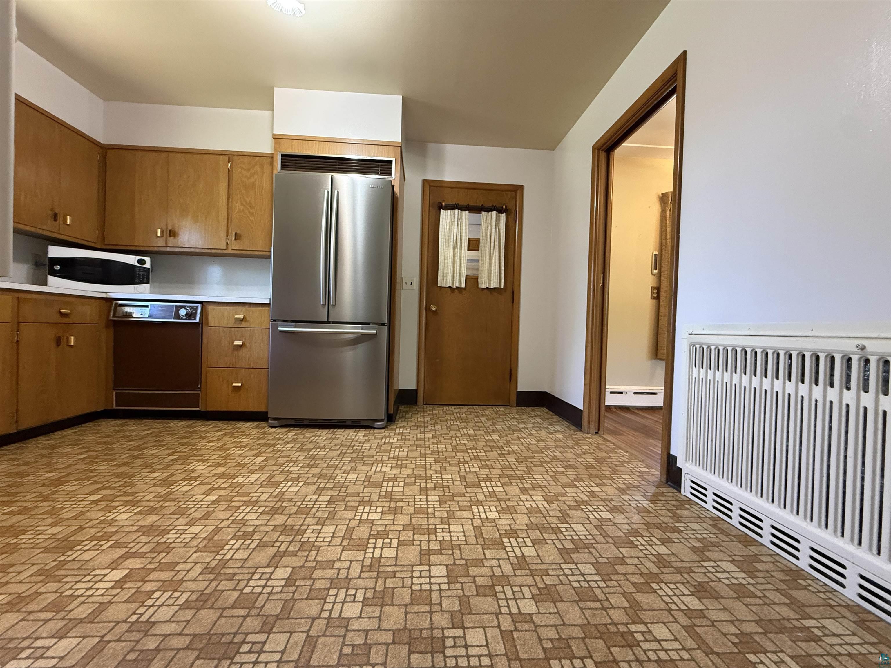 607 3rd Street Northeast Chisholm, MN 55719 - Photo 11 of 32 Kitchen featuring wood cabinetry, white countertops, a stainless steel French door refrigerator, and a built-in dishwasher