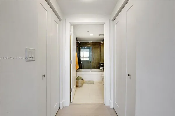 a view of a hallway with wooden floor and a bathroom