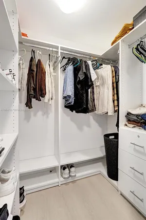 a view of walk in closet with clothes and shoes