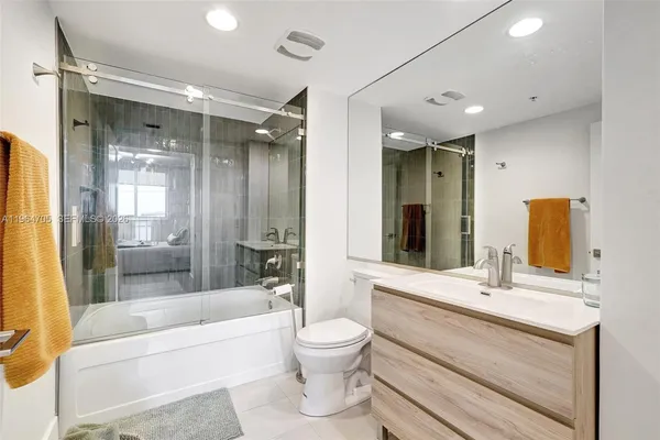 a bathroom with a bathtub shower sink mirror and toilet