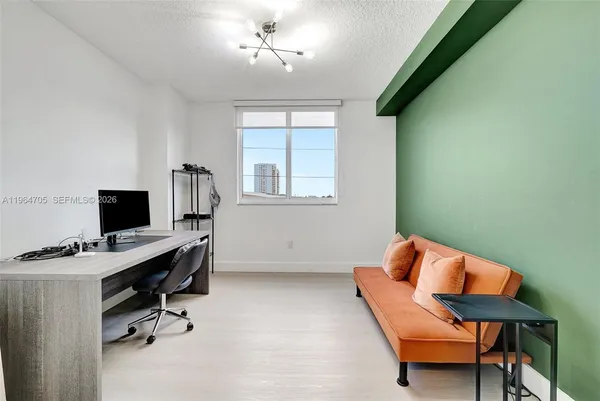 a view of a workspace with furniture and a window