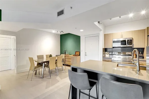 a kitchen with stainless steel appliances kitchen island granite countertop a dining table chairs microwave and sink