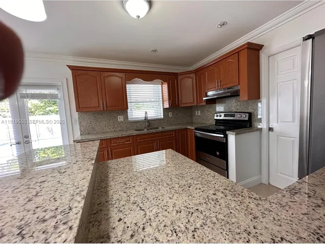 a kitchen with stainless steel appliances granite countertop a stove a sink and a refrigerator
