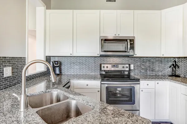 a kitchen with granite countertop a stove a sink and a microwave