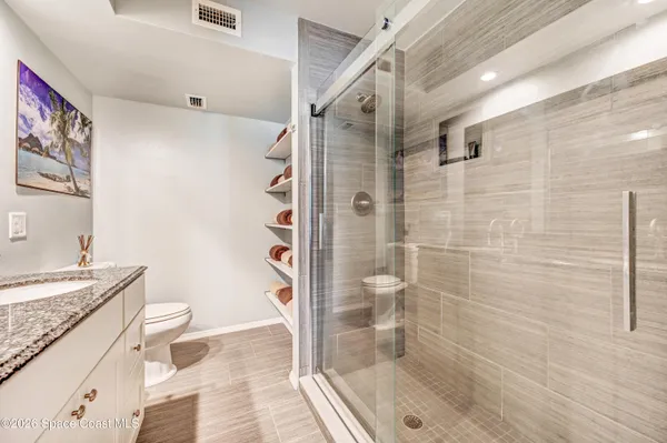 a bathroom with a granite countertop shower a sink and toilet