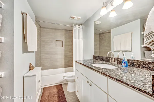 a bathroom with a granite countertop double vanity sink a mirror and a bathtub