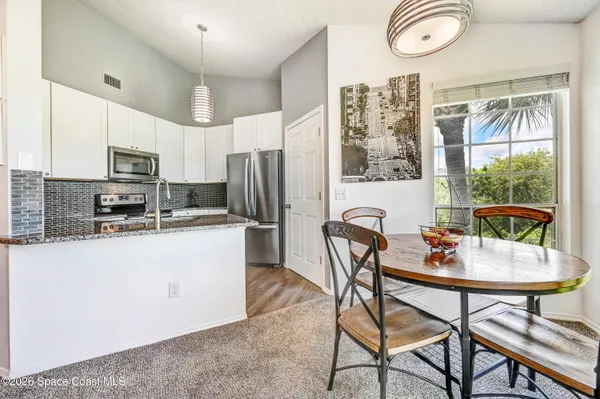 a kitchen with a refrigerator a stove a sink a dining table and chairs