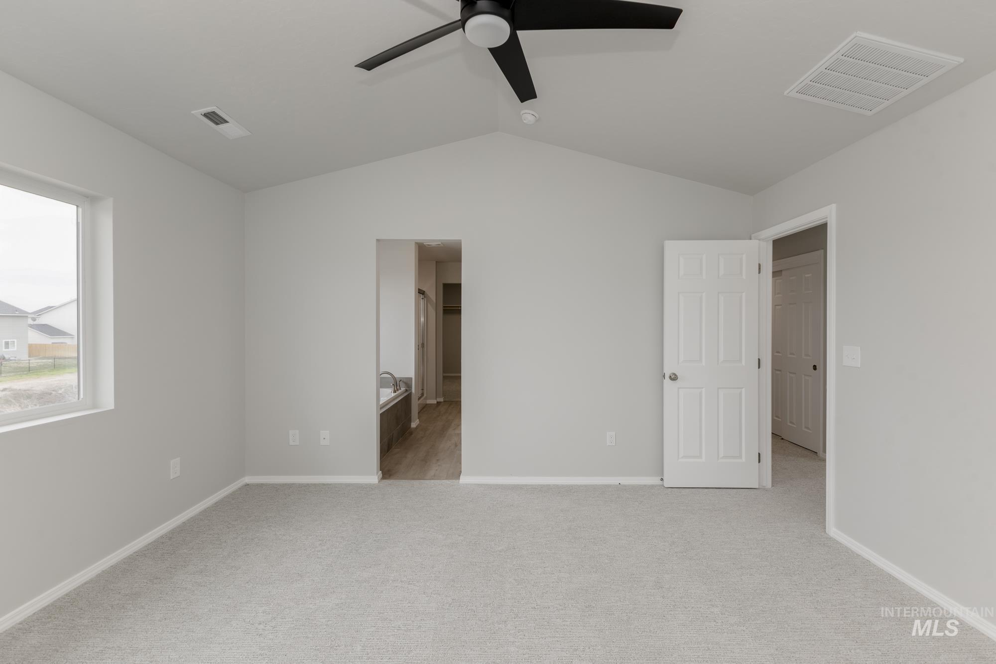 12842 Ropers Street Nampa, ID 83651 - Photo 25 of 29 Spacious room featuring vaulted ceilings, light gray carpeting, a large window, a black ceiling fan, and access to an adjoining bath with wood-finish flooring