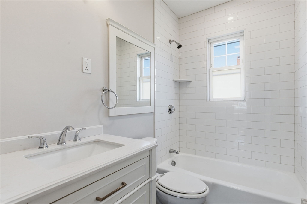 113 Minot Street, Unit 2 Boston, MA 02122 - Photo 18 of 34 a bathroom with a granite countertop sink toilet a mirror and shower
