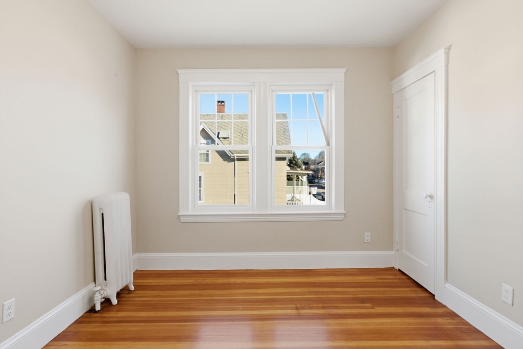 113 Minot Street, Unit 2 Boston, MA 02122 - Photo 21 of 34 a view of an empty room with wooden floor and a window