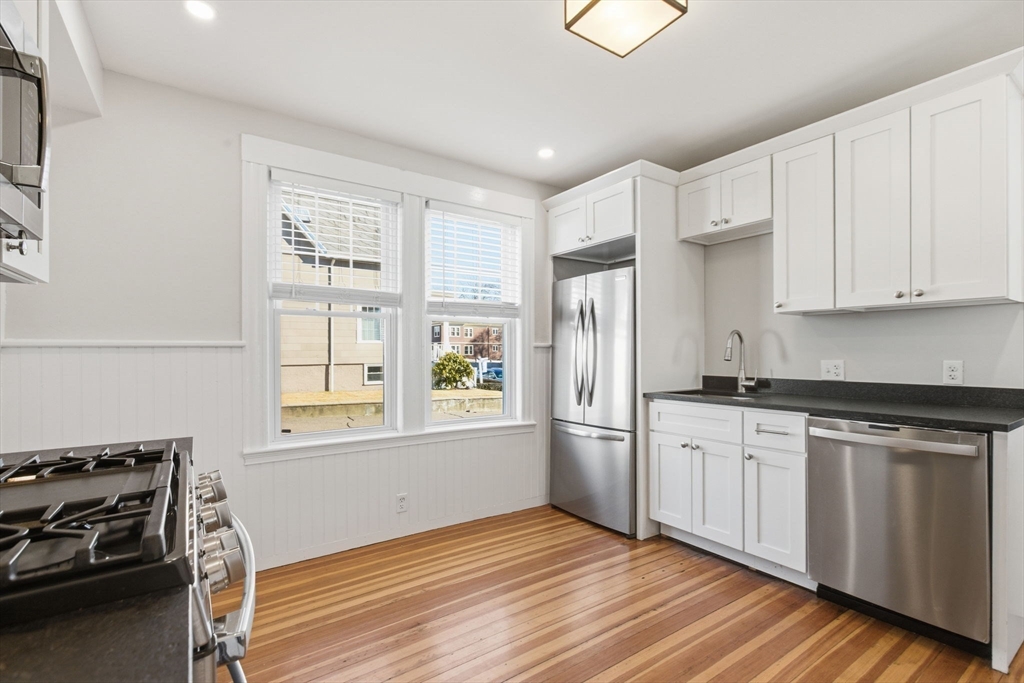 113 Minot Street, Unit 2 Boston, MA 02122 - Photo 4 of 34 a kitchen with stainless steel appliances granite countertop a stove a sink and a refrigerator with wooden floors