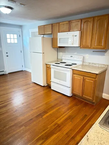 a kitchen with granite countertop a stove a sink and a refrigerator