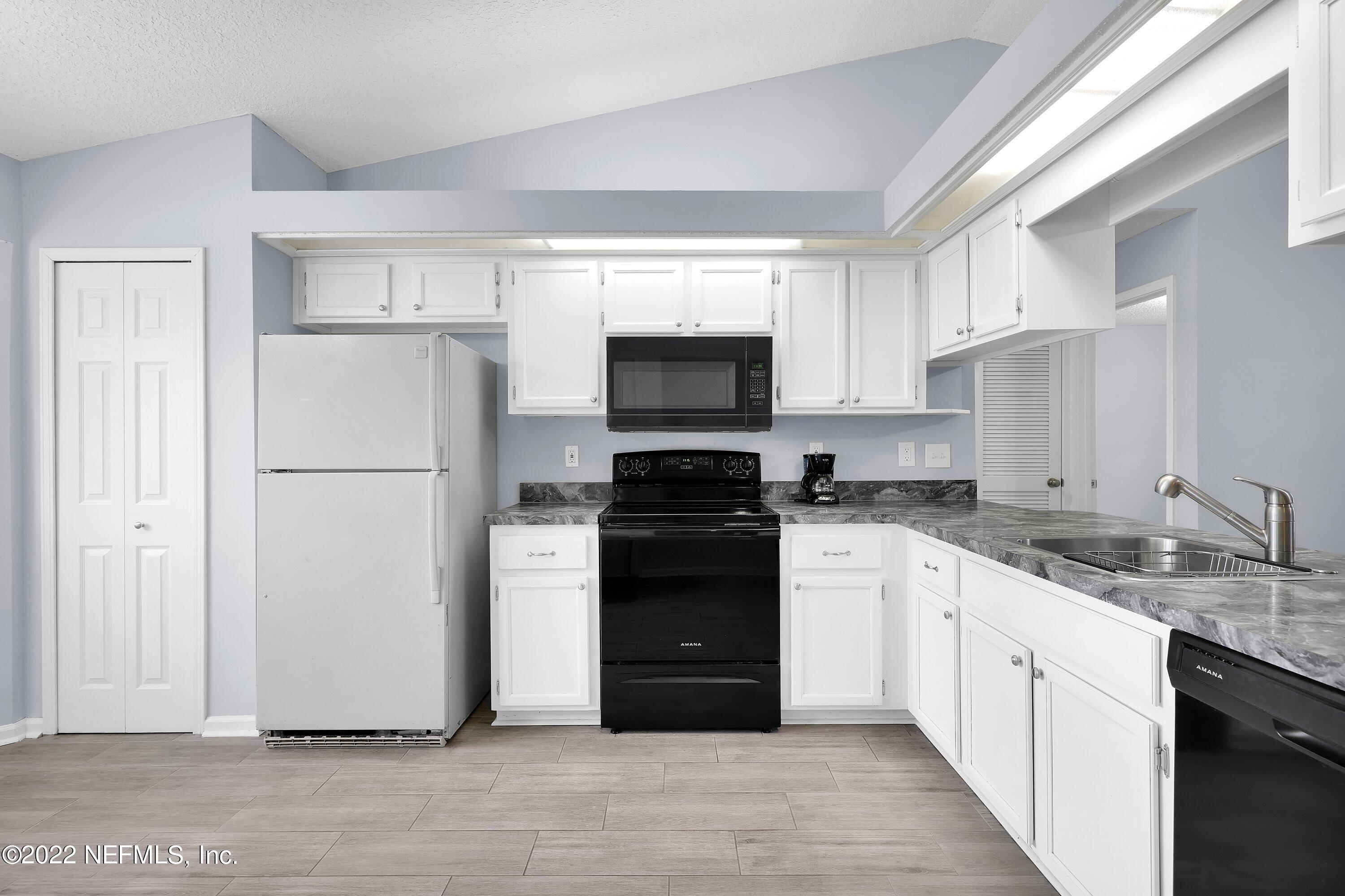 3248 Dowitcher Lane Orange Park, FL 32065 - Photo 7 of 26 a kitchen with a refrigerator stove and white cabinets