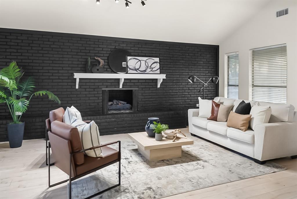 13103 Halwin Circle Dallas, TX 75243 - Photo 3 of 15 Living room featuring wood finished floors, vaulted ceiling, brick wall, a fireplace, and an accent wall