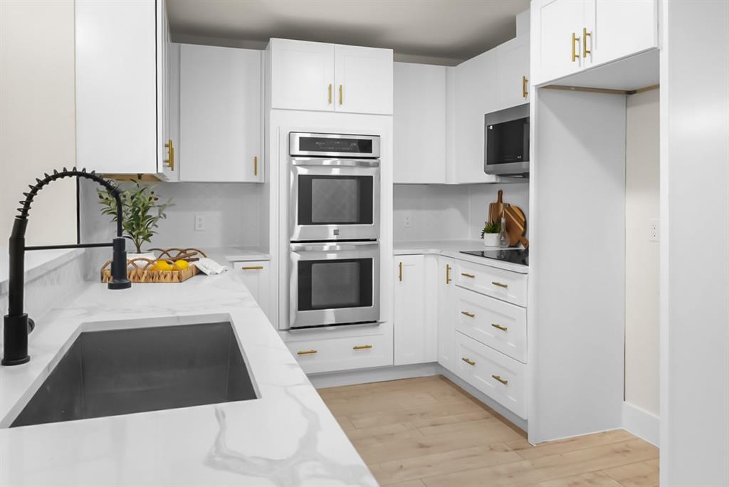 13103 Halwin Circle Dallas, TX 75243 - Photo 6 of 15 Kitchen with stainless steel appliances, white cabinetry, light wood-style floors, and light stone countertops