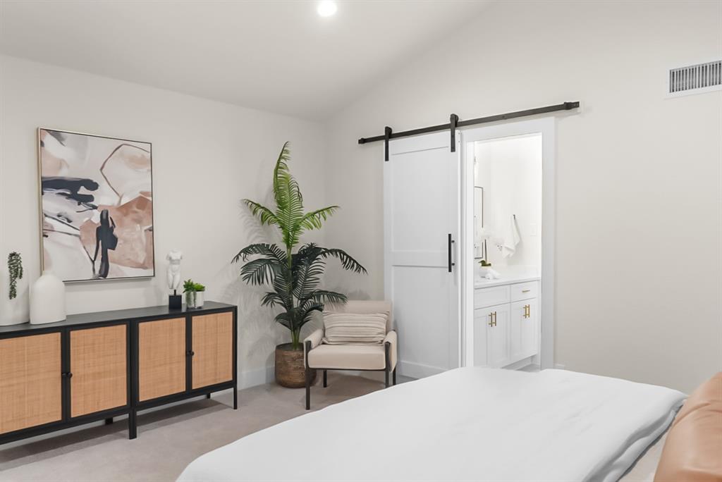 13103 Halwin Circle Dallas, TX 75243 - Photo 9 of 15 Bedroom with a barn door, lofted ceiling, light carpet, and ensuite bathroom