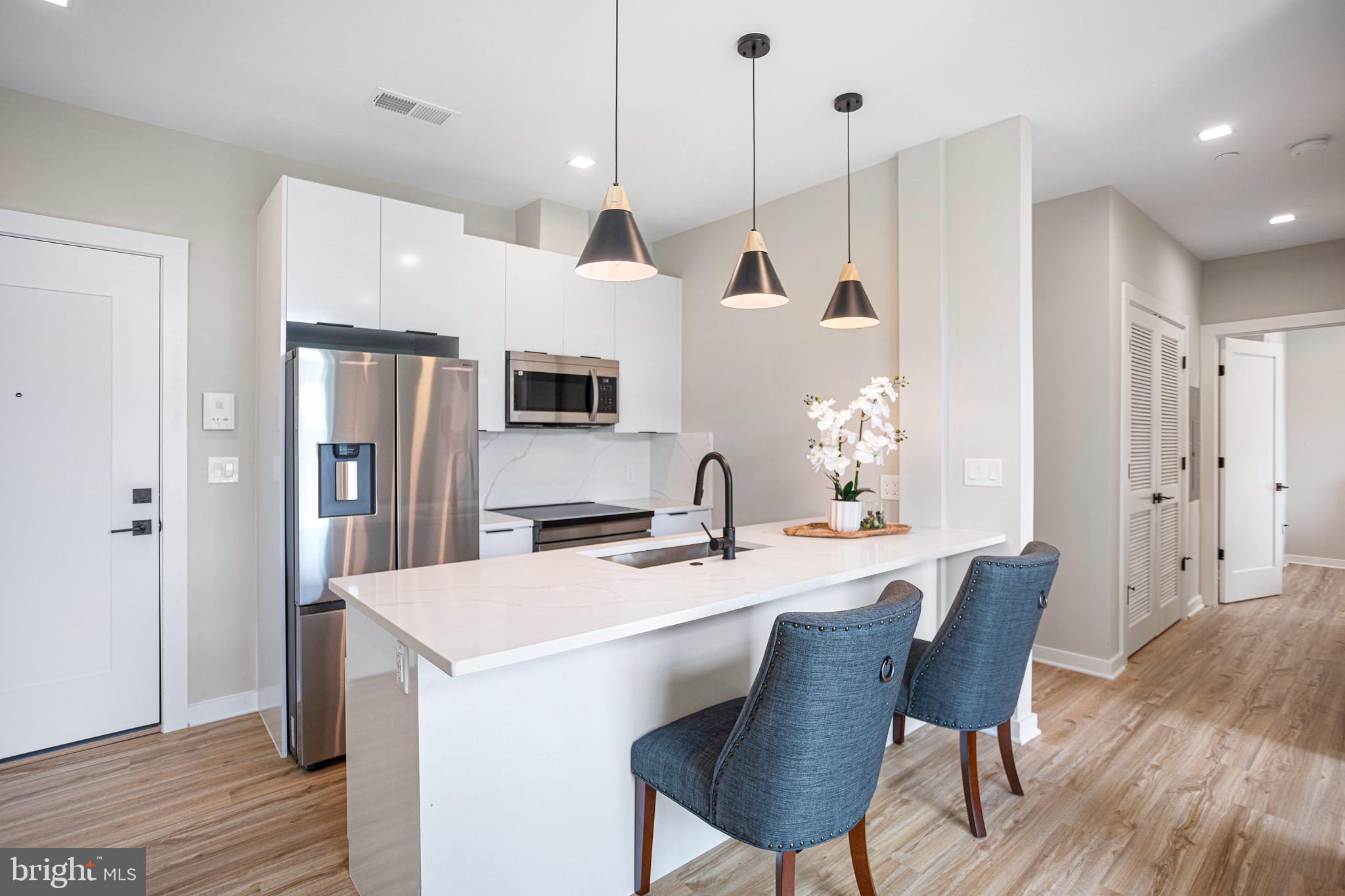 1358 Florida Avenue Northeast, Unit 401 Washington, DC 20002 - Photo 3 of 12 a kitchen with stainless steel appliances kitchen island granite countertop a table chairs and a refrigerator