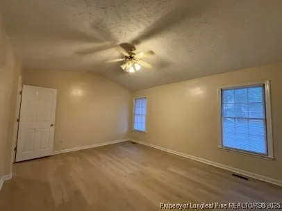 an empty room with windows and fan