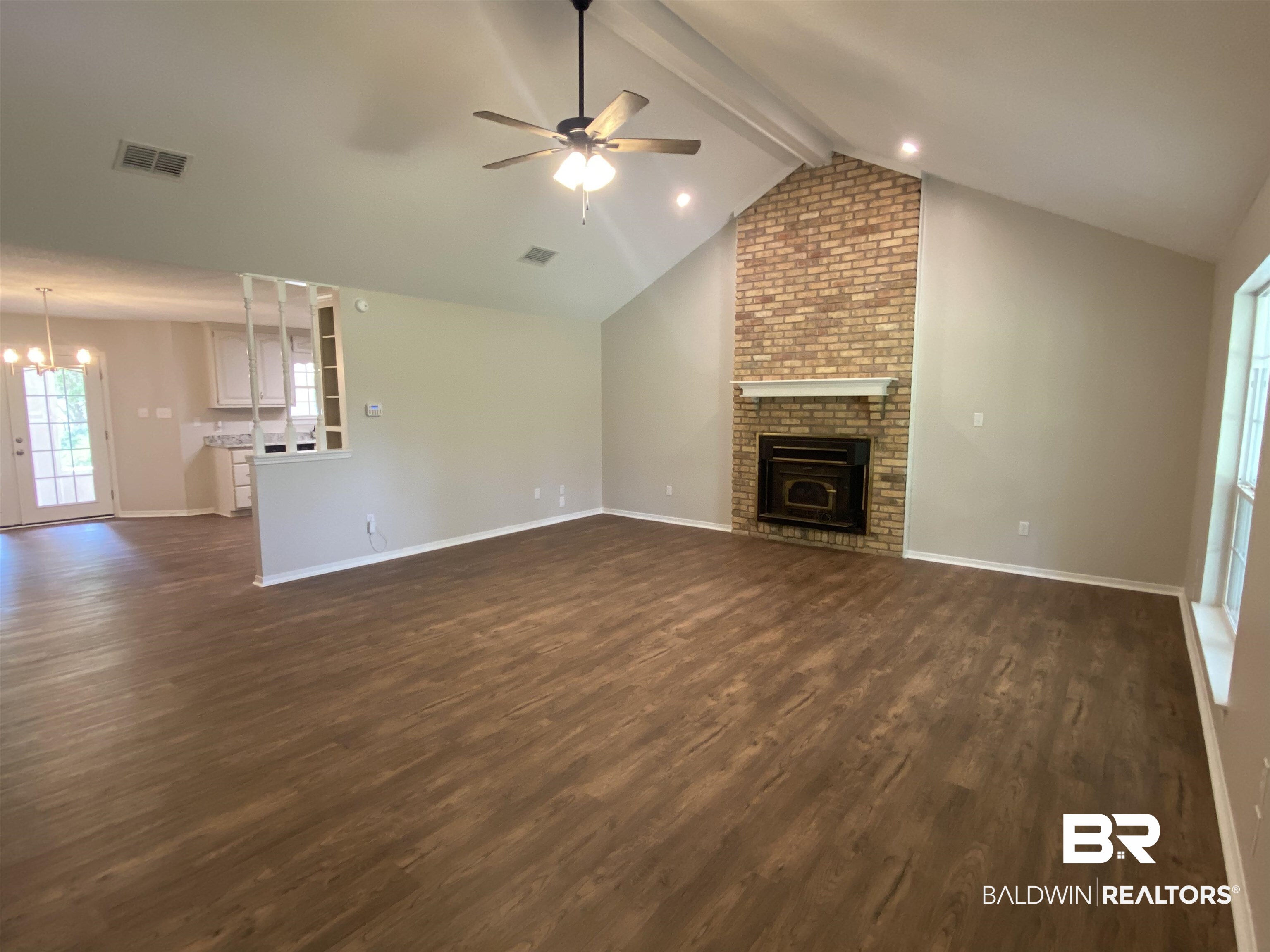 12150 Lee Bishop Road Irvington, AL 36544 - Photo 8 of 26 Unfurnished living room with a brick fireplace, ceiling fan with notable chandelier, baseboards, dark wood-type flooring, and visible vents