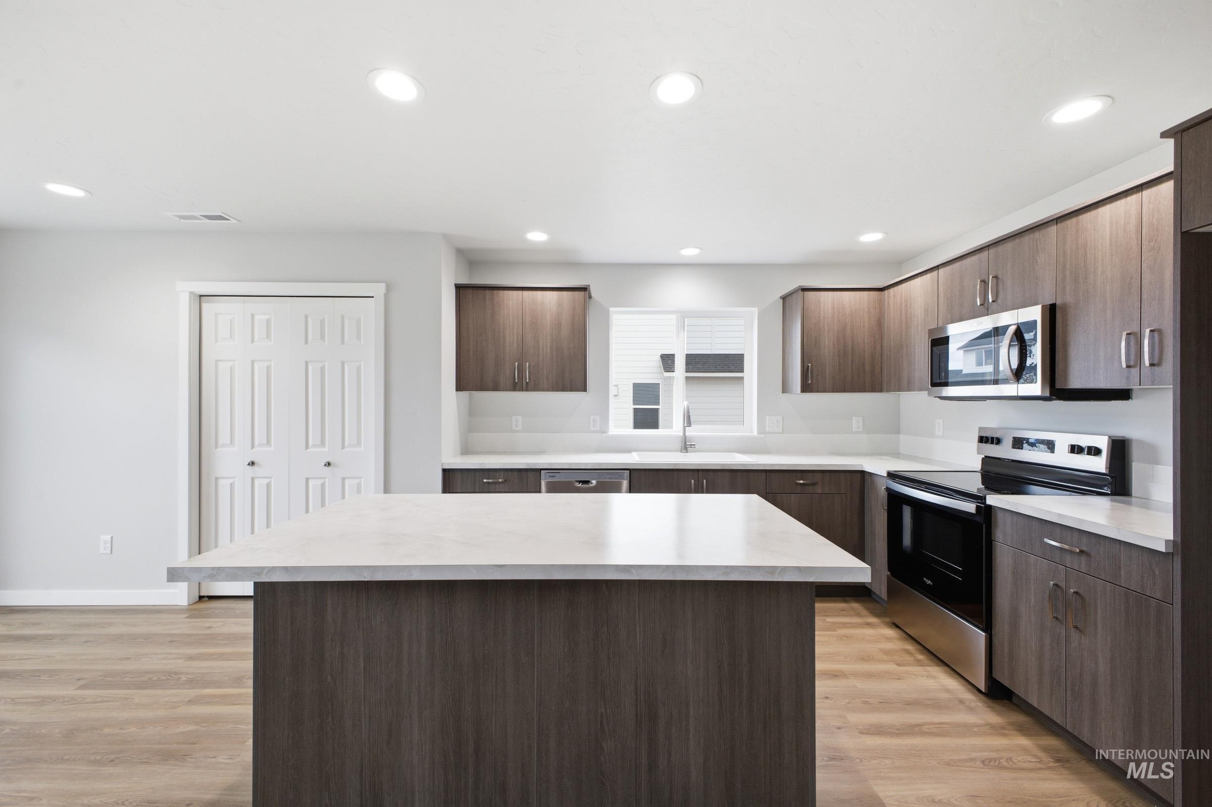 13702 Inman Court Caldwell, ID 83607 - Photo 5 of 23 Kitchen with stainless steel appliances, a center island, light countertops, dark wood finish cabinetry, and recessed lighting