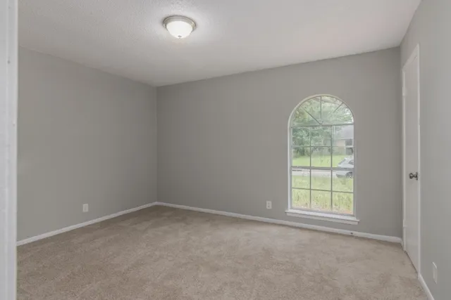 a view of an empty room with a ceiling fan and window