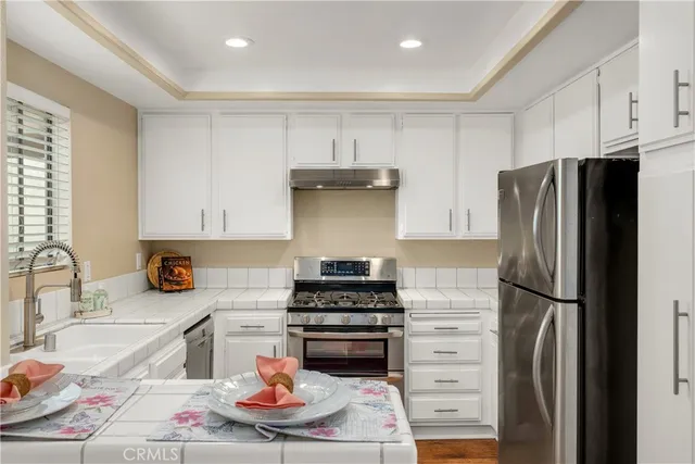 a kitchen with stainless steel appliances granite countertop a refrigerator and a stove top oven