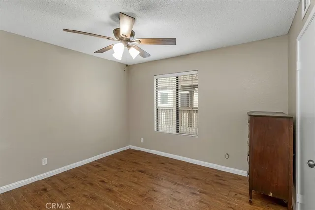 an empty room with wooden floor closet and windows
