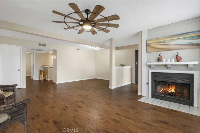 a view of an empty room with wooden floor and a fireplace