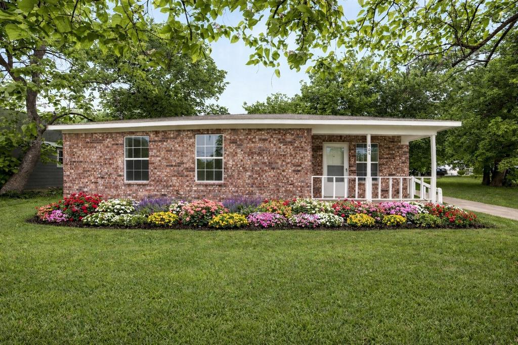 This property features a brick exterior, a white front porch with railings, and a well-maintained lawn