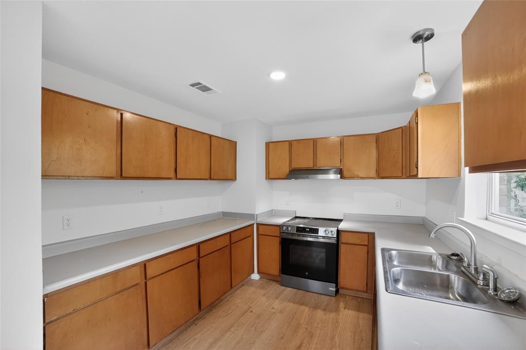 808 Park Street Commerce, TX 75428 - Photo 11 of 29 The kitchen features extensive wooden cabinetry, a stainless steel oven and range hood, and a double basin sink