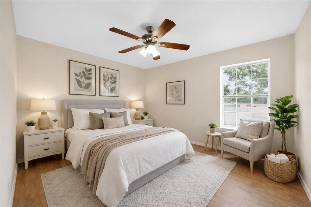 808 Park Street Commerce, TX 75428 - Photo 12 of 29 This inviting room features light-colored walls, wood-look flooring, and a ceiling fan with integrated lighting - Virtually Staged
