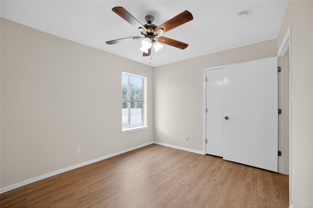 808 Park Street Commerce, TX 75428 - Photo 14 of 29 This room features light-colored walls, a window providing natural light, and wood-look flooring