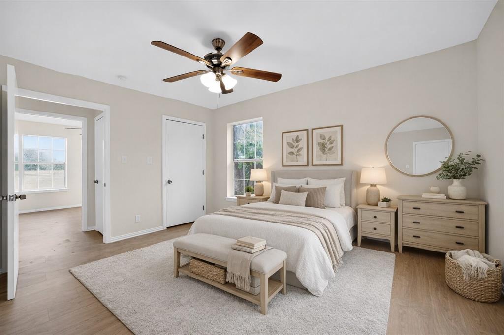 808 Park Street Commerce, TX 75428 - Photo 16 of 29 The property features light-colored walls, hardwood flooring, and a ceiling fan with light fixture - Virtually Staged