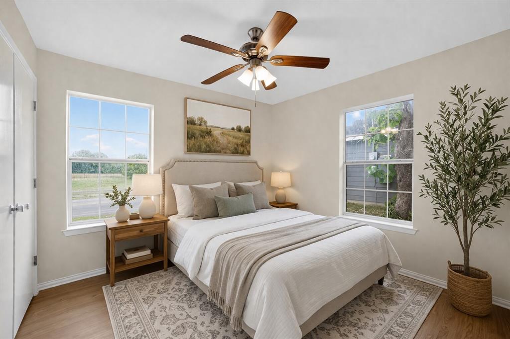 808 Park Street Commerce, TX 75428 - Photo 20 of 29 This room features hardwood flooring, two windows providing natural light, and a ceiling fan with integrated lighting - Virtually Staged