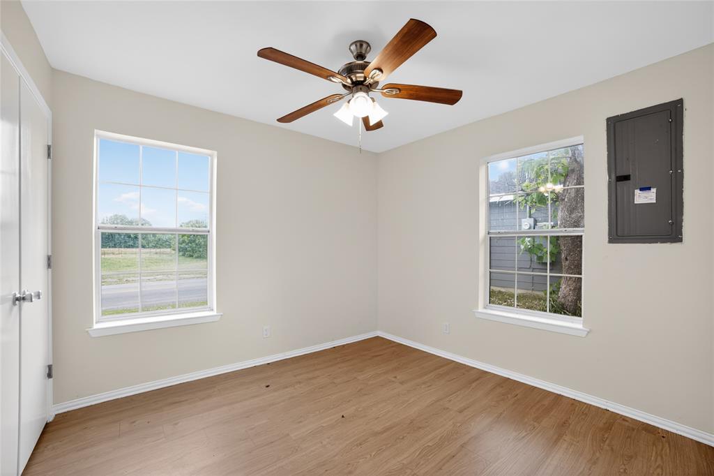 808 Park Street Commerce, TX 75428 - Photo 21 of 29 This room features light-colored walls, wood-style flooring, a ceiling fan with light fixture, and two windows