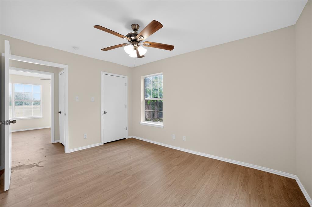 808 Park Street Commerce, TX 75428 - Photo 23 of 29 Room featuring light wood-style flooring, a window providing natural light, and a ceiling fan with integrated lighting
