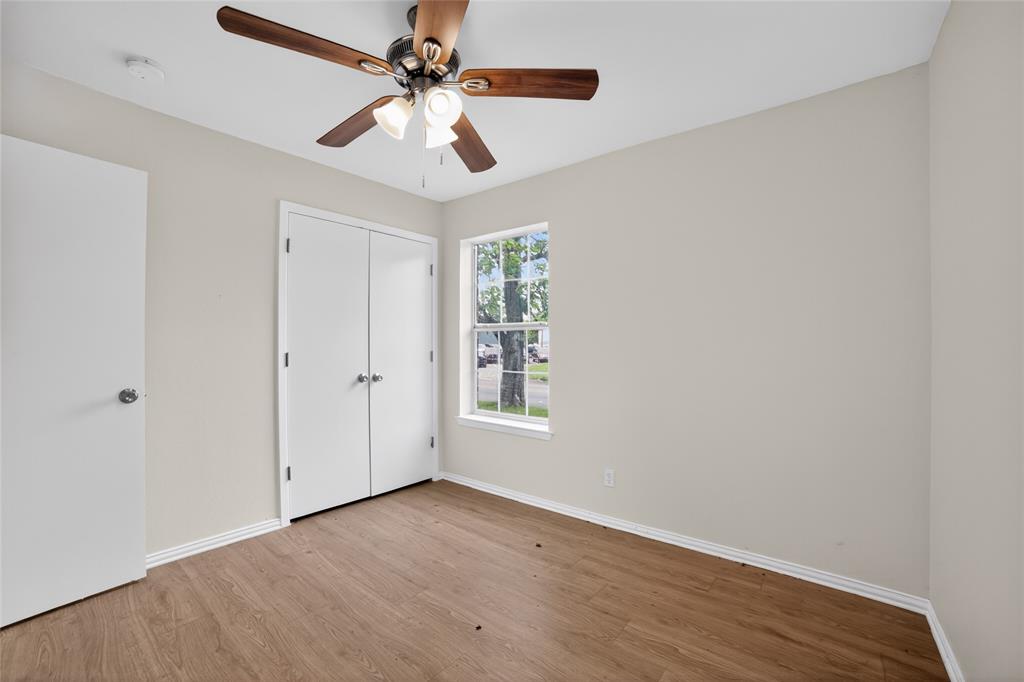808 Park Street Commerce, TX 75428 - Photo 25 of 29 This room features wood-look flooring, a window providing natural light, and a ceiling fan with integrated lighting