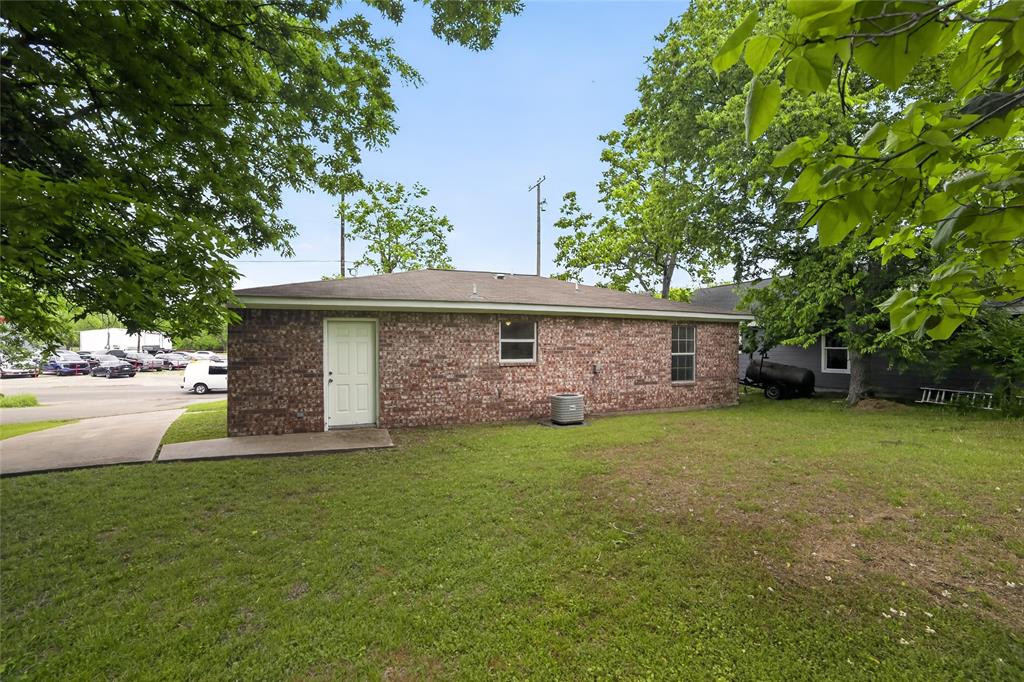 808 Park Street Commerce, TX 75428 - Photo 27 of 29 The property features a brick exterior, a well-maintained lawn, and mature trees providing shade